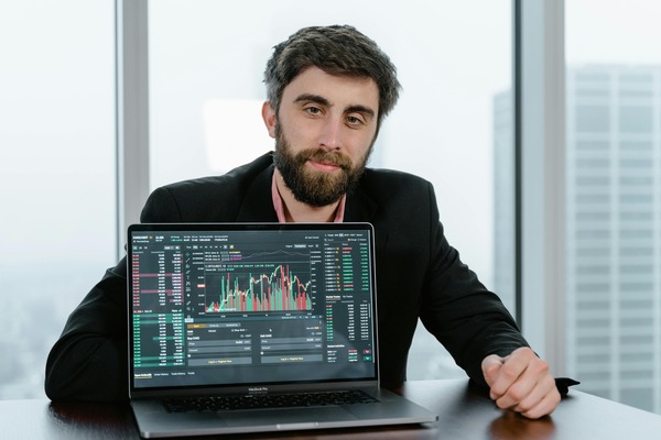 Man at a laptop with trading charts in a modern office
