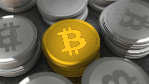 Gold Bitcoin coin on top of silver coin stacks