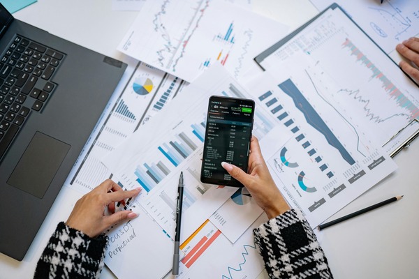 Smartphone with a trading app over printed market reports