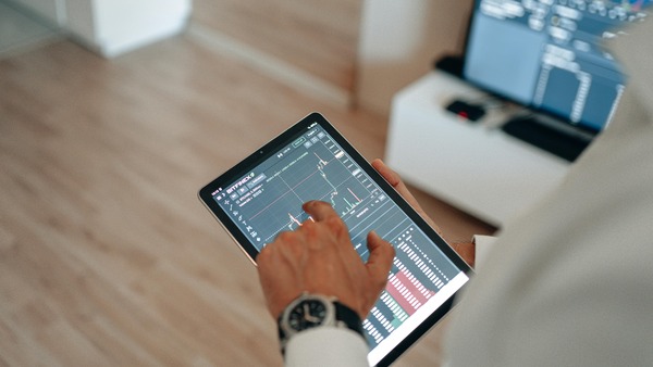 Hand tapping a trading chart on a tablet screen