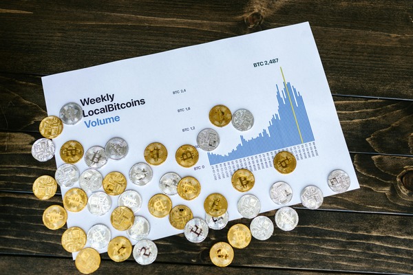 Crypto coins scattered around a printed volume chart