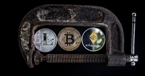 Crypto coins held in a rusty metal clamp