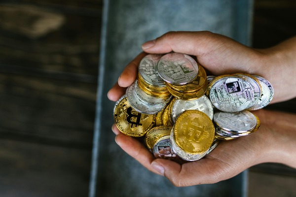 Hands holding a pile of gold and silver crypto coins