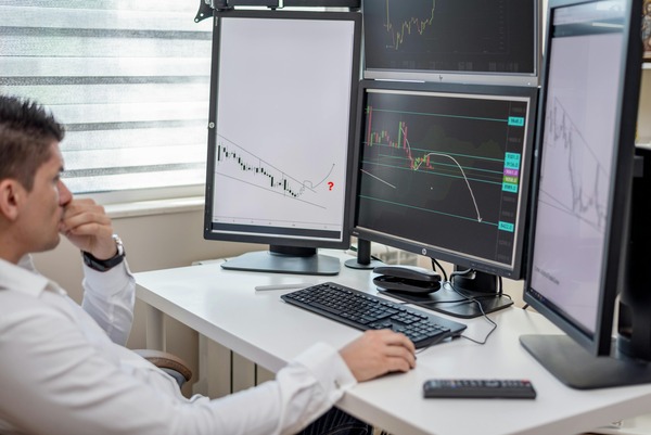 Trader analysing price charts on multiple monitors