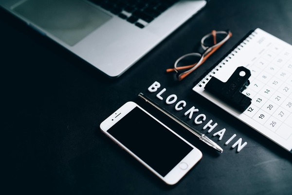 Notebook, phone and blockchain letter tiles on a dark desk