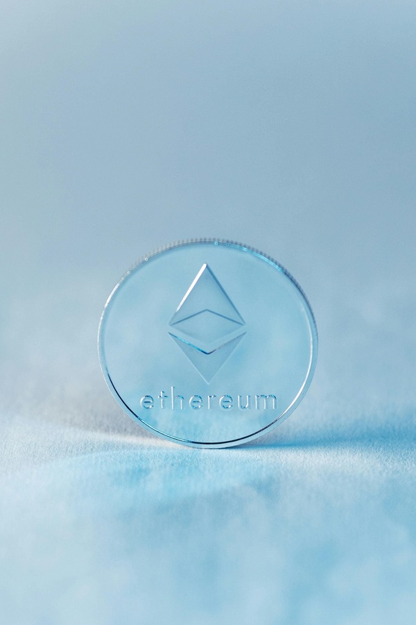 Transparent Ethereum-style coin on a pale blue surface