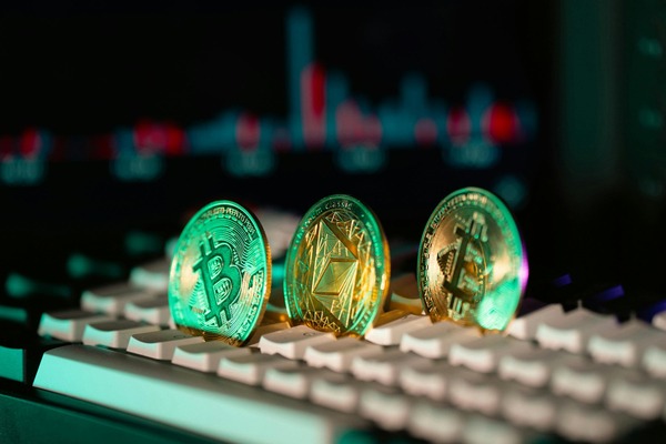 Three glowing crypto coins standing on a keyboard