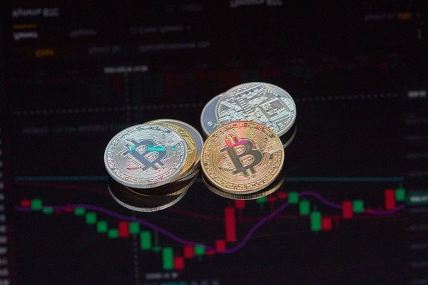 Stacked crypto coins in front of a candlestick chart
