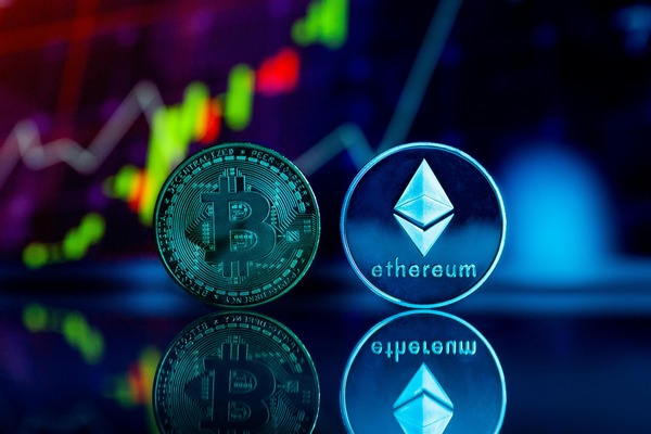 Two crypto coins reflected over a neon market chart