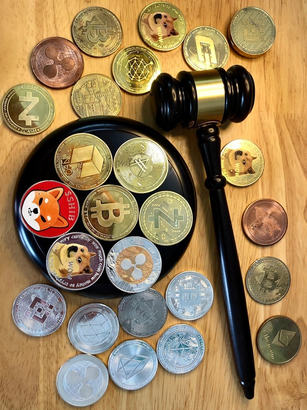 Assorted crypto coins on a wooden table beside a gavel