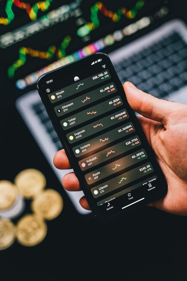 Hand holding a smartphone with a live crypto trading chart