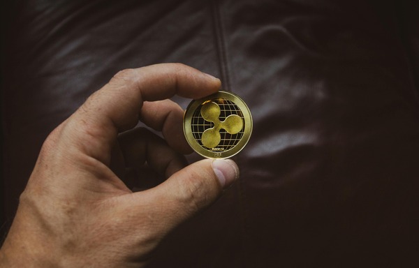 Hand holding a gold XRP coin close up
