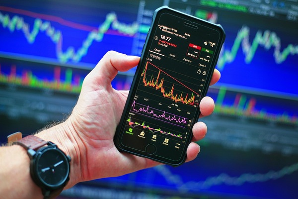 Hand holding a phone with a crypto price chart